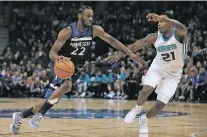  ?? STACY BENGS/THE ASSOCIATED PRESS ?? Minnesota Timberwolv­es forward Andrew Wiggins, left, drives the ball around Charlotte Hornets guard Treveon Graham during Sunday’s game in Minneapoli­s.