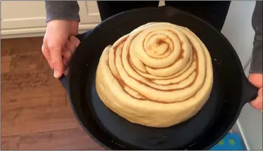  ?? WHITNEY RUTZ VIA AP ?? Whitney Rutz displays a large cinnamon roll before putting it in the oven April 11 in her home in Portland, Ore. Rutz baked cinnamon rolls to help raise funds for Oregon Food Bank.