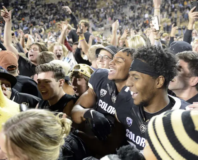  ?? Cliff Grassmick, Daily Camera ?? Colorado wide receiver Brenden Rice, center left, celebrates the win over Oregon State with quarterbac­k Brendon Lewis and Buffs fans on the field Saturday night at Folsom Field in Boulder.