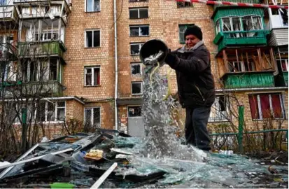  ?? SERGEI SUPINSKY/AFP/GETTY IMAGES ?? A resident of Kyiv dumped out broken glass after a Russian drone exploded nearby.