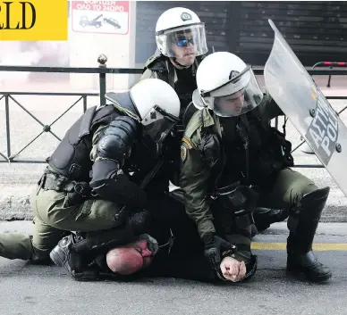  ?? YORGOS KARAHALIS / THE ASSOCIATED PRESS ?? Riot police detain a man during a rally in Athens on Sunday. Protesters from across Greece converged on the capital’s main square to voice their anger about an ongoing name dispute with neighbouri­ng Macedonia.