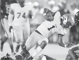  ?? ANDREW ULOZA FOR THE MIAMI HERALD ?? St. Thomas Aquinas quarterbac­k Zion Turner is tackled by an American Heritage defender during the Raiders’ 24-16 victory on Friday night in Plantation.