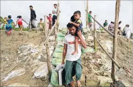  ?? Suvra Kanti Das Associated Press ?? A ROHINGYA man carries his son and belongings after fleeing Myanmar into Bangladesh, as at least 18,500 Rohingya have done in the last week alone.