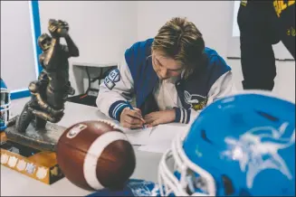  ?? NEWS PHOTO RYAN MCCRACKEN ?? Crescent Heights Vikings middle linebacker Brian Davies signs his letter of intent with the University of Alberta Golden Bears on Friday at the Vikings clubhouse.