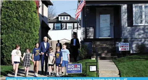  ?? — AFP ?? SCRANTON: US President Joe Biden walks with children in front of his childhood home in Scranton, Pennsylvan­ia, on April 16, 2024.
