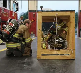  ?? SUBMITTED PHOTOS ?? In confined space training, firefighte­rs maneuver inside a box containing multiple wires.