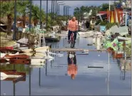  ?? GIANNIS MOISIADIS — INTIME NEWS VIA AP ?? A man rides a bicycle among debris after a storm at Nea Plagia village in Halkidiki region, northern Greece, Thursday. A powerful storm hit the northern Halkidiki region late Wednesday.