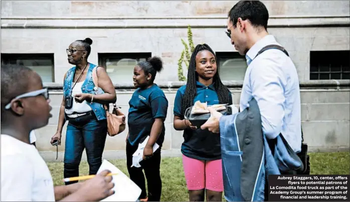  ?? ERIN HOOLEY/CHICAGO TRIBUNE ?? Aubrey Staggers, 10, center, offers flyers to potential patrons of La Comodita food truck as part of the Academy Group’s summer program of financial and leadership training.