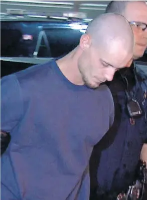  ?? CBC CALGARY ?? Officers lead suspect Dustin Duthie into the Calgary Police Service arrest processing unit late Tuesday night, Duthie is the lone suspect in a triple slaying.