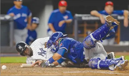  ?? The Associated Press ?? The ball rolls away as Toronto Blue Jays catcher Luke Maile, right, collides with New York Yankees’ Didi Gregorius, who scored during the eighth inning of their AL game in New York on Monday. The Blue Jays lost 6-3.