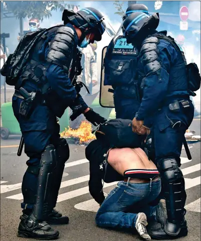  ??  ?? CLASH: Police arresting a protester in Paris yesterday, where demonstrat­ors held up anti-vaccine placards, inset left