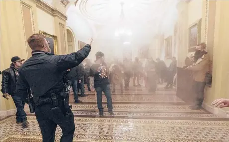  ?? MANUEL BALCE CENETA/AP ?? Smoke fills the walkway outside the Senate chamber as supporters of President Trump are confronted by U.S. Capitol Police officers inside the Capitol on Jan. 6 in Washington. The acting chief of the Capitol Police apologized to Congress on Tuesday.