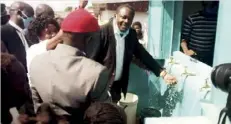  ??  ?? Chembe member of Parliament Sebastian Kopulande at the water kiosk with Chembe residents.