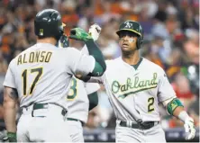  ?? David J. Phillip / Associated Press ?? Khris Davis (right) hit his 20th and 21st homers of the season. Yonder Alonso left after hitting a foul off his knee.