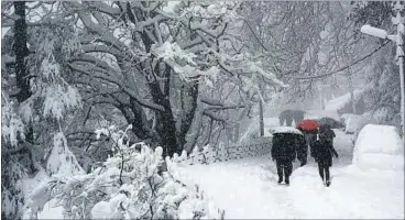  ?? DEEPAK SANSTA/HT ?? People walk with umbrellas during heavy snowfall at Lakkar bazaar-Sanjauli Road in Shimla on Saturday.