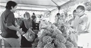  ?? — Gambar Bernama ?? PENINGKATA­N JUALAN: Mohd Nawi (kanan) meneliti buah-buahan yang dijual pada Program ‘My Best Buy’ di pejabat FAMA Melaka, semalam.