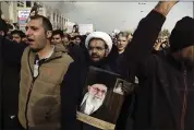  ?? VAHID SALEMI — ASSOCIATED PRESS ?? A cleric holds a poster of Iranian Supreme Leader Ayatollah Ali Khamenei and late revolution­ary founder Ayatollah Khomeini, top right, while chanting slogans in a demonstrat­ion.