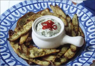  ?? SARA MOULTON VIA AP ?? This Jan. 9 photo shows potato skins baked with roasted garlic rosemary butter and an onion kale dip spiked with fresh chiles. This dish is from the recipe “Decadent Snacks for the Super Bowl” by Sara Moulton.