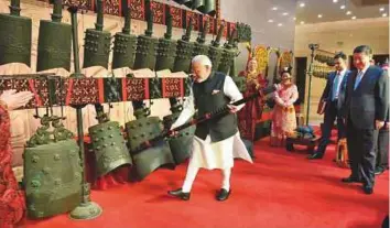  ?? AFP ?? (Above) Prime Minister Narendra Modi plays an instrument as Chinese President Xi Jinping looks on during their visit at Hubei Provincial museum in Wuhan, China, yesterday. (Right) Modi shaking hands with Jinping in Wuhan. The two heads of states are...