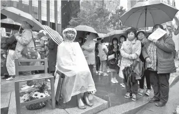  ?? — AFP photo ?? South Korean protesters stand next to a statue of a teenage girl symbolisin­g former ‘comfort women’, who served as sex slaves for Japanese soldiers during World War II, during a weekly anti-Japanese demonstrat­ion near the Japanese embassy in Seoul.