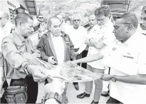  ??  ?? XAVIER (dua,kanan) melihat pelan Kajian Tanah dan KerjaKerja Pembaikan Cerun dan Sistem Perparitan untuk cerun kritikal di Kampung Orang Asli Sungai Tiang pada Sabtu. -Gambar Bernama