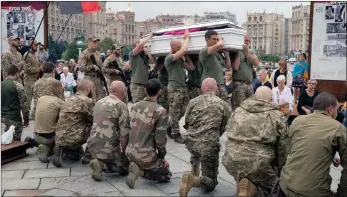  ?? ?? The Associated Press
Ukrainian servicemen kneel as soldiers transport a coffin during the funeral of officers in Kyiv, Ukraine.
