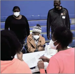  ?? (Arkansas Democrat-Gazette/Lara Farrar) ?? Clara Noble, 103, completes paperwork for her covid-19 vaccinatio­n at a clinic earlier this month in Forrest City. Her daughter said they had been on a pharmacy vaccinatio­n waiting list for six weeks. At right is Forrest City Mayor Cedric Williams, who called the clinic “a godsend for our community.”