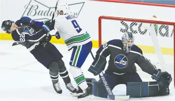  ?? KEVIN KING ?? Canucks forward J.T. Miller, centre, drops Winnipeg Jets forward Mason Appleton as goaltender Laurent Brossoit deals with a shot in Winnipeg on Tuesday night. The Jets won 5-2.