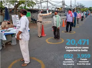  ?? PTI ?? SOCIAL DISTANCING: A security personnel conducts thermal scanning of vendors before they enter the Okhla vegetable market during the lockdown in New Delhi on Wednesday. —