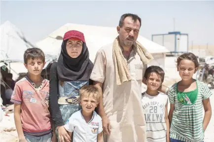  ??  ?? A photo released by Save The Children shows a resident from Raqqa standing with his children outside a tent in Ain Issa, Syria. (AFP)