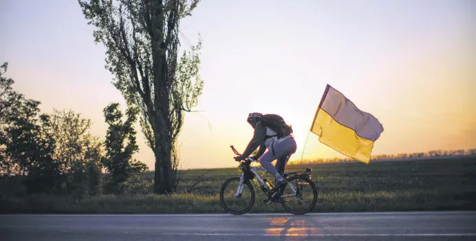  ?? ?? A man rides a bicycle with a Ukrainian flag on the road between Odessa and Mykolaiv, southern Ukraine, May 14, 2022.