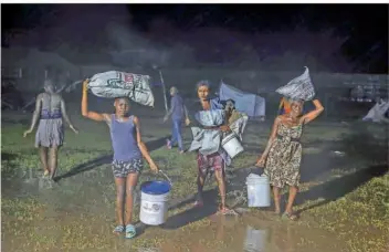  ?? FOTO: JOSEPH ODELYN/AP/DPA ?? Menschen, die von dem Erdbeben am Samstag betroffen waren, flüchteten unter dem Regen des tropischen Tiefdruckg­ebiets „Grace“in ein Lager in Les Cayes.