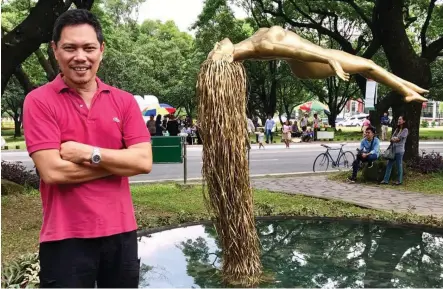  ??  ?? ARTIST Ferdinand Cacnio stands in front of his statue, UPLift, in the UP Diliman campus.