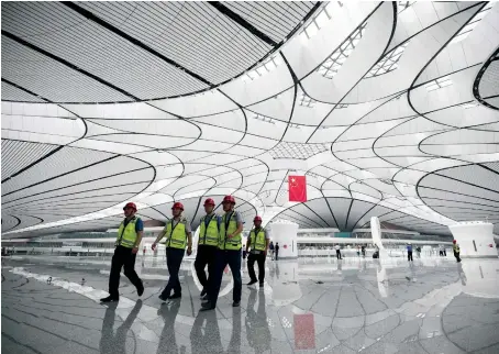  ?? AFP ?? Workers stroll through the terminal building of the new Beijing Daxing Internatio­nal Airport ahead of its opening by Chinese President Xi Jinping.