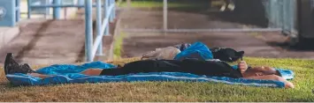  ??  ?? PUBLIC BED: A man sleeps outside the old Australia Post office on Grafton St. Picture: MARC McCORMACK