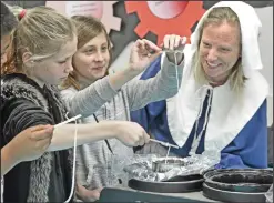  ??  ?? (Left)Fifth-grade teacher, Melinda Katambwa, right, dressed as a Colonial era woman, assists fifth-graders Kiley Norman, left, and Lily Drummond as they dip string into hot wax to make a candle while participat­ing in Colonial Day at Newhall Elementary School on Dec. 16, 2016. (Right) Newhall Elementary students listen as Byrd Holland and other seniors from Atria Senior Living read stories to them on Sept. 21, 2017. The California School Dashboard, which was released in December, evaluates school performanc­es.