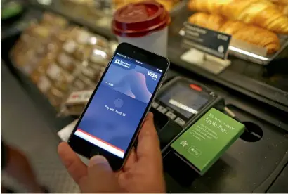  ??  ?? a customer uses an iPhone to pay via the apple Pay system at the check-out till inside a store in London.