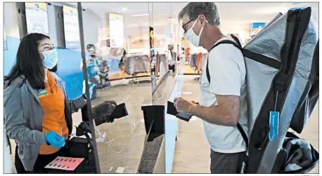  ?? LM OTERO/AP ?? A cashier and customer are separated by Plexiglas at a water park in Grande Prairie, Texas. Water parks across the state were allowed to reopen Friday.