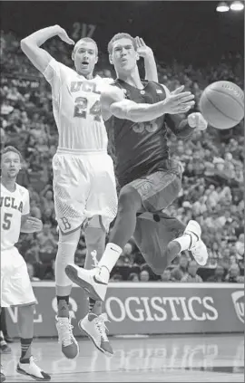  ?? Ethan Miller Getty Images ?? STANFORD’S DWIGHT POWELL doesn’t seem comfortabl­e about it, but he makes a pass under pressure from UCLA’s Travis Wear.