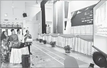  ??  ?? (From left) Hashimah, Ripin and others watch a slide show on the history of the school after the launching ceremony.