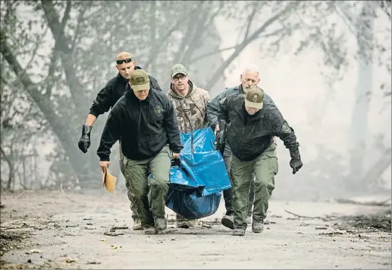  ?? JOSH EDELSON / AFP ?? Agentes de la oficina del Sheriff de Yuba County retiran el cadáver de una persona de una de las casas arrasadas en Paradise