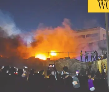  ?? ASAAD NIAZI / AFP VIA GETTY IMAGES ?? Onlookers watch and record as a massive fire engulfs the coronaviru­s isolation ward of Al-hussein hospital in the southern Iraqi city of Nassiriya Monday evening. The fire was sparked by faulty wiring that ignited an oxygen tank.