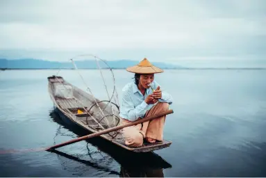  ??  ?? © Tales from the Roads Less Traveled by Pie Aerts, published by teNeues, www.teneues.com, www.mendo.nl, A fisherman lights up a cigarette during a morning run on Inle Lake, Myanmar, Photo © 2019 Pie Aerts. All rights reserved.