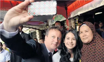  ??  ?? David Cameron takes a selfie at a Jakarta street market during the Indonesian leg of his tour