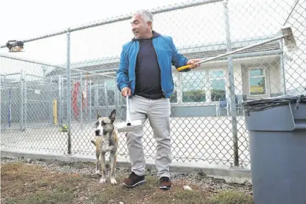  ?? Photos by Scott Strazzante / The Chronicle ?? Above: Cesar Millan cleans up a dog run as he films at the Oakland shelter. Below: Jessica Fox cuddles a shelter pup.