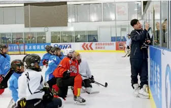  ??  ?? A coach explains ice hockey techniques to his trainees, August 30, Haidian District, Beijing