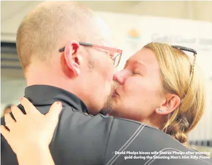  ??  ?? > David Phelps kisses wife Sharee Phelps after winning gold during the Shooting Men’s 50m Rifle Prone
