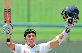  ??  ?? Kusal Mendis raises his bat and helmet in celebratio­n of scoring a century during the third day of the opening Test match between Sri Lanka and Australia at the Pallekele Internatio­nal Cricket Stadium - AFP