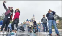  ?? JEFF GRITCHEN — STAFF PHOTOGRAPH­ER ?? Visitors take selfies in front of Sleeping Beauty Castle during the last day before Disneyland closed in Anaheim on March 13, 2020. California announced new theme park guidelines and an opening date as part of a refresh of its economic plan.