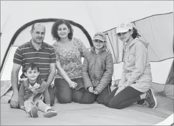  ?? KATIE SMITH/THE GUARDIAN ?? Marwan Alkhouri, back left, his wife Samia, and their children, 10-year-old Antoon, 15-year-old Anna and three-yearold Andre, sit in the tent they successful­ly erected after learning how to do so at Stanhope campground during a Parks Canada Learn-to-Camp event on the weekend.